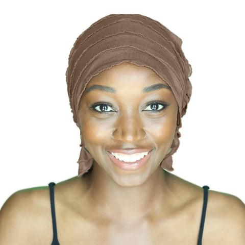 A smiling woman wears the Chemo Beanies® Sara brown chemo beanie and a black spaghetti strap top, photographed against a plain white background.