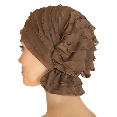 A woman in profile wears the Chemo Beanies® Sara textured brown chemo beanie, featuring layered, ruffled fabric that covers her hair and neck, against a white background.