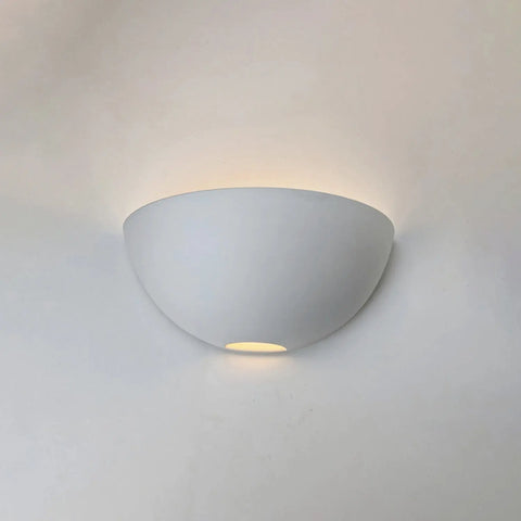 The Aegina Sconce by A19 Artisan Lighting is a modern, USA-made wall light handcrafted in California, with a ceramic half-bowl design that casts soft up and down light against any plain white wall.