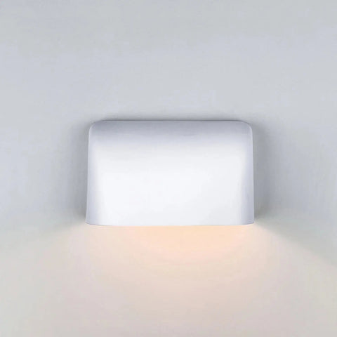 The Balboa Downlight Sconce by A19 Artisan Lighting is a USA-made, handcrafted white rectangular wall light that casts a soft, warm downward glow onto a light gray wall.