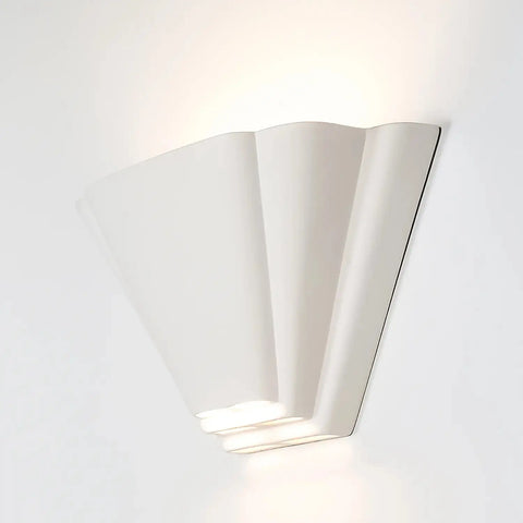 The Modern USA-Made Bermuda Sconce by A19 Artisan Lighting, handcrafted in California, features a white fan-shaped design that casts soft up and down light. Its curved, layered segments offer a subtle sculptural accent on any plain wall.