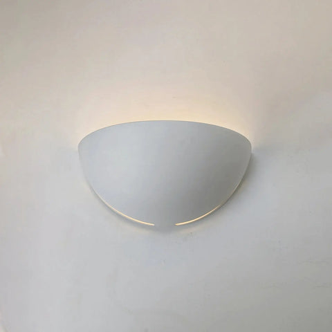 The Capri Sconce by A19 Artisan Lighting is a handcrafted, USA-made modern white half-sphere wall light that casts soft upward LED smart bulb illumination, creating a gentle glow on your walls.