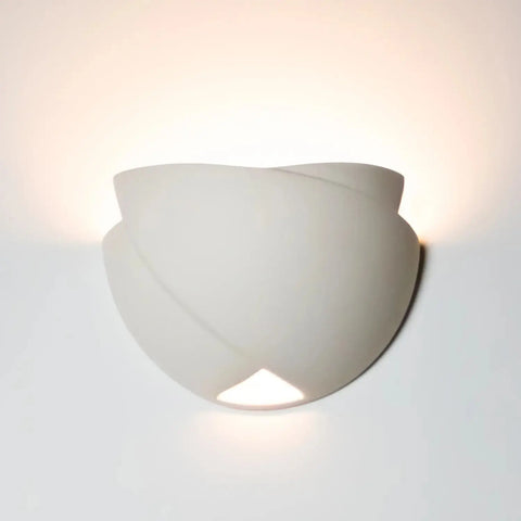 The Modern USA-Made Ceylon Sconce by A19 Artisan Lighting, handcrafted in California, features a curved, layered design that casts soft up-light and a subtle down-glow against light-colored walls.