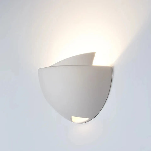 The Modern USA-Made Ceylon Sconce by A19 Artisan Lighting, handcrafted in California, features smooth curves and a minimalist design. It casts soft upward and downward light, creating a subtle wall glow.