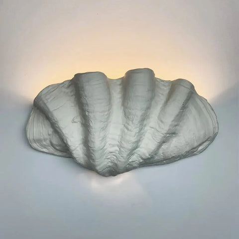 The Modern USA-Made Fiji Sconce from A19 Artisan Lighting, handcrafted in California, is a wall-mounted light shaped like a croissant that emits a soft, warm glow on any plain white wall.