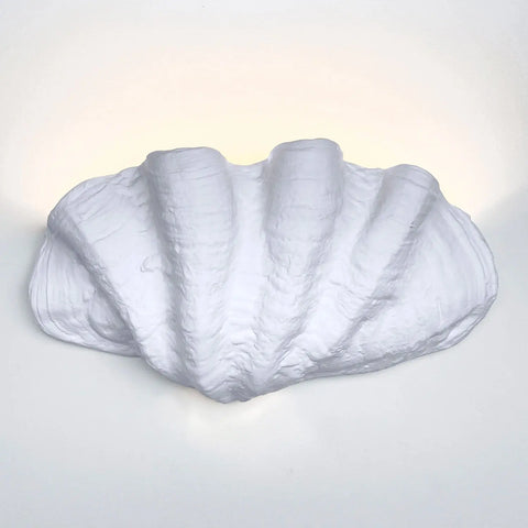 The Fiji Sconce by A19 Artisan Lighting is a handcrafted, white, seashell-shaped wall light—made in California—glowing softly against your wall.
