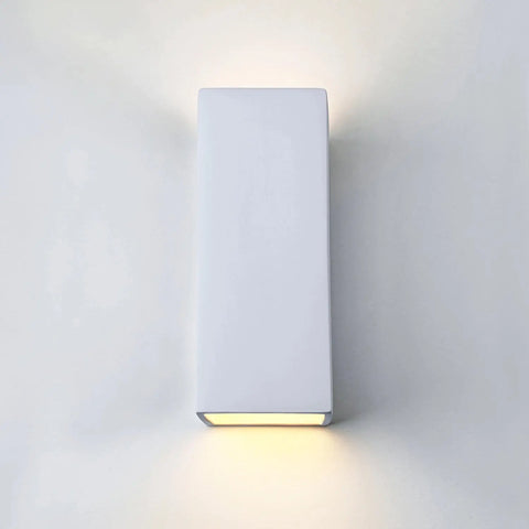 The Modern USA-Made Flores Sconce by A19 Artisan Lighting, handcrafted in California, has a rectangular white design with a custom finish and casts soft up-and-down light for a subtle glow on any light-colored wall.