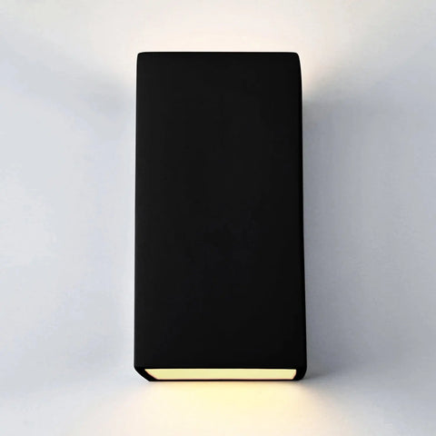 The Flores Sconce by A19 Artisan Lighting is a modern black rectangular wall fixture, handcrafted in California, emitting soft white light above and below. Customize the finish or upgrade to LED smart bulbs for added convenience.