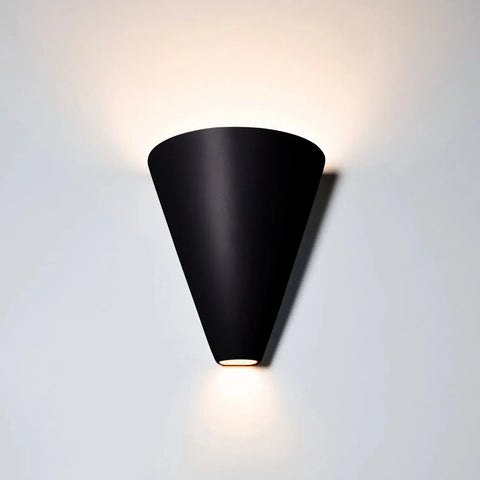 The Gotlandia Sconce by A19 Artisan Lighting is a USA-made, handcrafted black wall light featuring a cone shape and energy-efficient LED bulbs that cast soft upward light for a gentle halo effect.