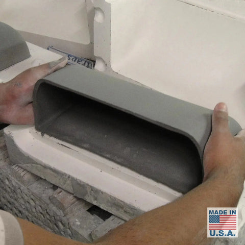 A person holds the Gran Balboa Sconce, a gray, rectangular ceramic wall light with rounded edges, handcrafted in California by A19 Artisan Lighting. The Made in U.S.A. label and American flag are shown in the bottom right corner.