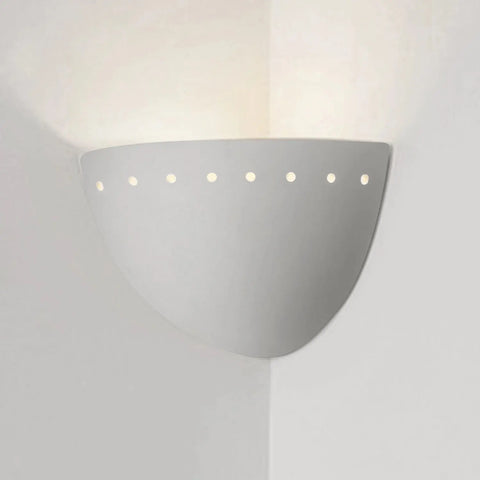 The Gran Cyprus Corner Sconce by A19 Artisan Lighting is a modern, USA-made white wall light with a curved design and small circular holes near the top, handcrafted in California to cast soft upward light in any corner.