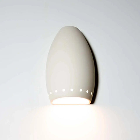 A white Grenada Downlight Sconce with a perforated urn-shaped design, illuminated from the inside, mounted on a wall.