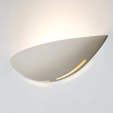 The Modern USA-Made Wall Lighting – Kauai Sconce by A19 Artisan Lighting features a curved metallic design, casts a soft LED glow on white walls, and is handcrafted in California for modern elegance.