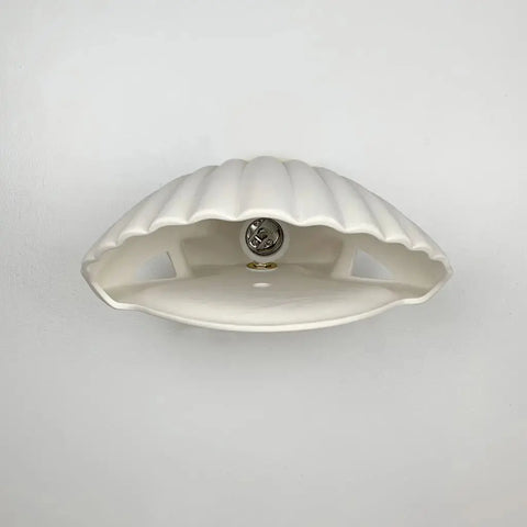 A19 Artisan Lighting’s Key Biscayne Sconce, a modern, handcrafted white ceramic wall light shaped like a clam shell, is made in California and designed for energy-efficient LEDs—a striking USA-made lighting accent.