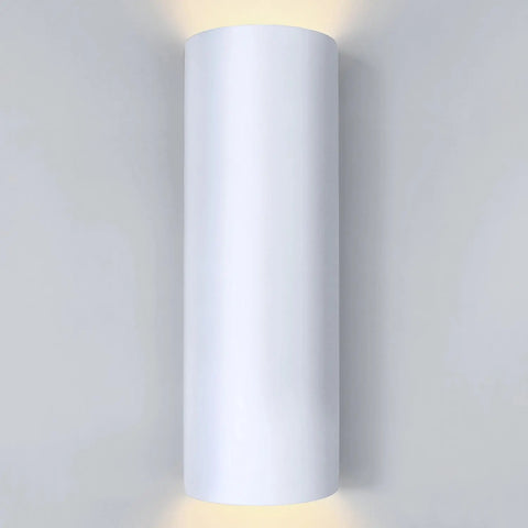 The Kos Sconce by A19 Artisan Lighting is a modern, cylindrical wall light handcrafted in California, emitting soft up and down lighting. Shown in white on a light gray wall.