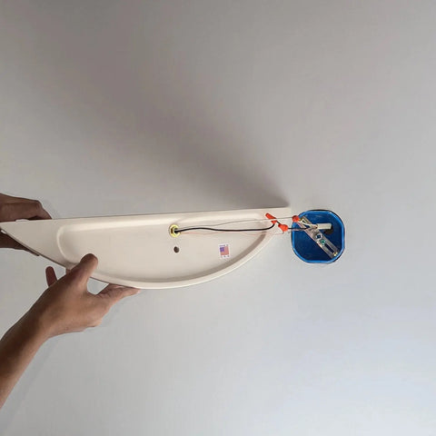 Hands holding the Modern USA-Made Wall Lighting – Maui Sconce by A19 Artisan Lighting, handcrafted in California, near a ceiling electrical box with exposed wiring, preparing for installation against a plain white ceiling.