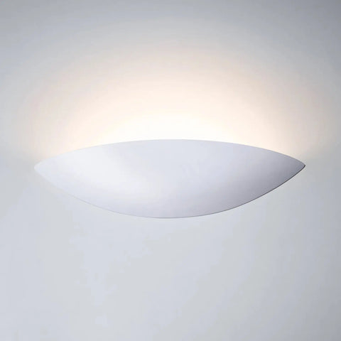 The Modern USA-Made Maui Sconce by A19 Artisan Lighting, handcrafted in California, emits soft upward light that gently illuminates a light gray wall with a subtle gradient.