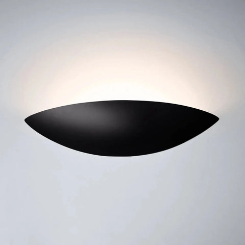 The Maui Sconce by A19 Artisan Lighting is a handcrafted, modern black wall light made in California, featuring an upward curved design that softly glows against the wall.