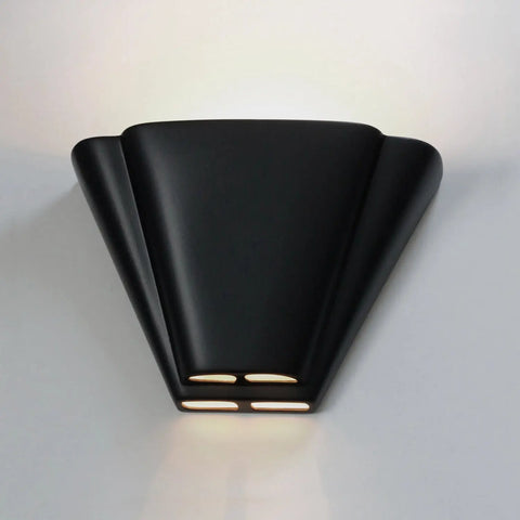 The Modern USA-Made Wall Lighting – Nova Scotia Sconce by A19 Artisan Lighting features a handcrafted black fan-shaped design with bottom cutouts, casting soft upward light. Made in California and perfect for mounting on a white wall.