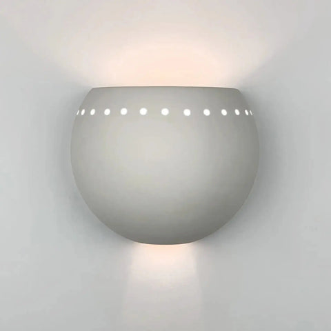 Handcrafted in California by A19 Artisan Lighting, the St Lucia Sconce is a modern USA-made wall fixture with energy-efficient LED lighting that casts soft, patterned light upward and downward through circular cutouts.