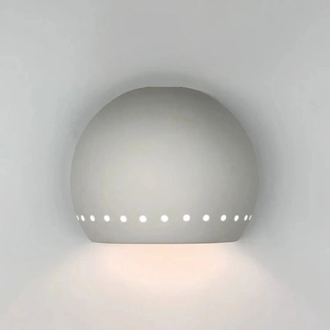 The Modern USA-Made St Vincent Downlight Sconce by A19 Artisan Lighting features a half-sphere ceramic design with circular holes near the edge, casting soft, ambient light downward—handcrafted in California.