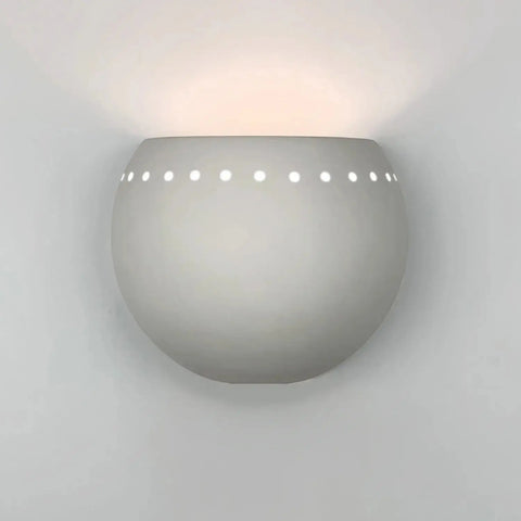 The St Vincent Sconce by A19 Artisan Lighting is a round, white ceramic wall light with small top-edge holes, casting soft upward light. Handcrafted in California, this modern fixture brightens any plain white wall.