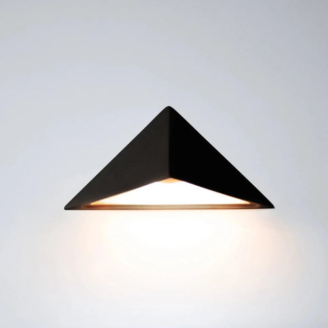 The Modern USA-Made Sumatra Downlight Sconce by A19 Artisan Lighting features a black triangular design with an energy-efficient LED, casting a gentle downward glow on the wall below. Handcrafted in California.