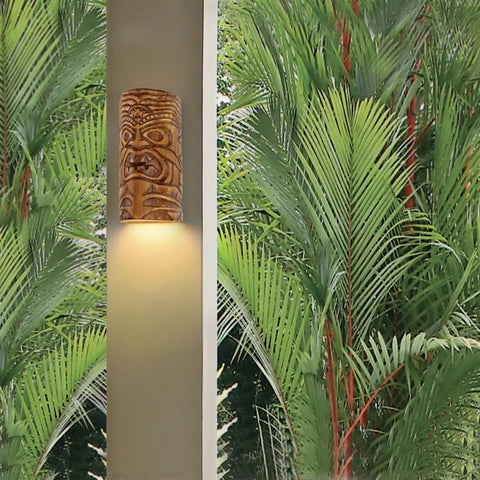 The Modern USA-Made Wall Lighting – Tiki Downlight Sconce by A19 Artisan Lighting, handcrafted in California, features a tiki mask cover that glows beside lush palms, adding Nature Collection vibes to your space.