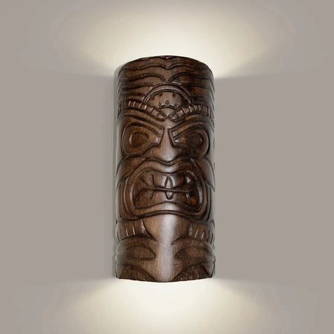 The Modern USA-Made Wall Lighting – Tiki Sconce by A19 Artisan Lighting is handcrafted in California, featuring a carved face design and LED smart bulbs that cast a warm glow on your neutral wall.