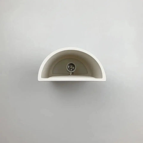 A19 Artisan Lightings Tilos Sconce is a handcrafted, modern wall light made in California, USA. Shown mounted on a plain, light gray wall and viewed from above, it features a sleek design for contemporary spaces.