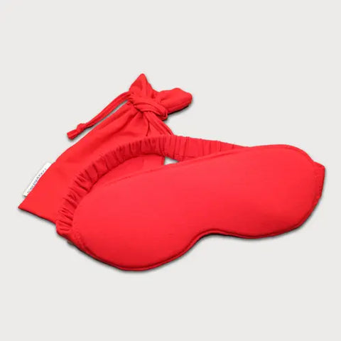 The Goodnighties Sleep Mask With Pouch features a vibrant red handcrafted mask with an elastic strap, paired with a matching drawstring pouch, displayed on a simple light background.