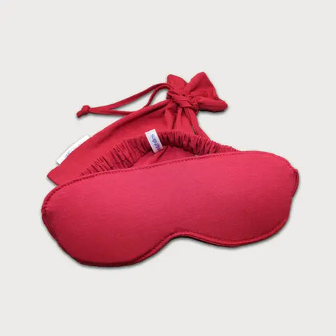 The Goodnighties Sleep Mask With Pouch features a handcrafted red fabric mask with an elastic strap, shown in front of its matching red drawstring pouch on a plain white background.