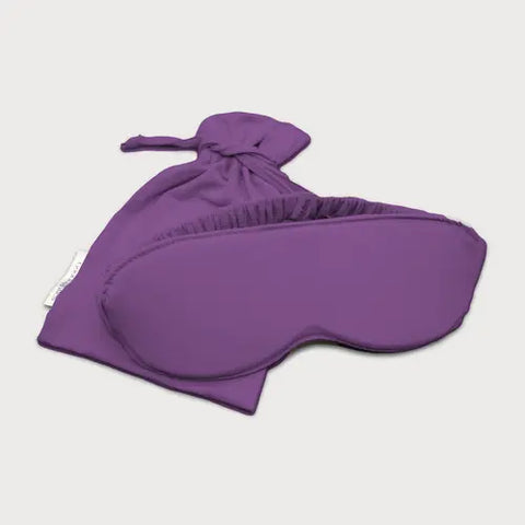 The Goodnighties Sleep Mask With Pouch is shown with gathered edges, displayed in front of a matching purple drawstring pouch on a white background.