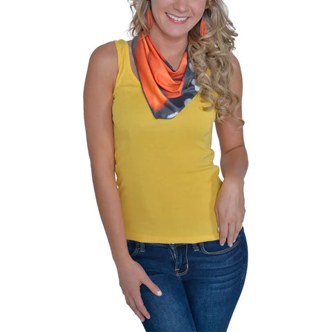 A woman with long curly blonde hair, in a yellow top and blue jeans, smiles with one hand on her hip, wearing the Spiritex | Sustainable Apparel Infinity Bandana | Monarch Butterfly and orange earrings against a white background.