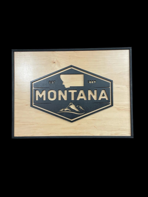 The Framed Montana Emblem Sign by B. James Design & Woodwork features a hexagonal Montana emblem with state outline, EST 1889, and mountain design, set on a birch background with a black frame.