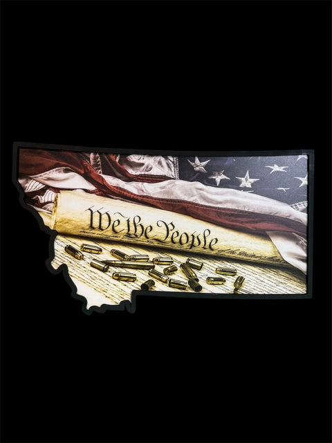 Featuring B. James Design & Woodwork’s Montana We the People Sign, this piece displays the U.S. Constitution’s “We the People,” an American flag, and bullets within a Montana-shaped sign on a black background—a unique décor choice.