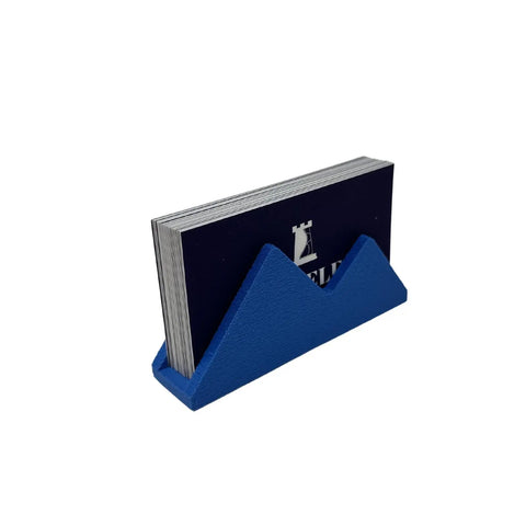 A stack of black business cards with a white chess rook rests in Chatelet Manufacturing’s Mountain Silhouette Design Business Card Holder, a stylish blue geometric accessory for displaying cards and decorating your desk.
