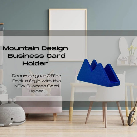 The Mountain Silhouette Design Business Card Holder Display by Chatelet Manufacturing sits on a white desk in a pastel-themed office with cute animal decor, adding style and organization to your modern workspace.