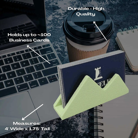 The Mountain Silhouette Design Business Card Holder Display by Chatelet Manufacturing sits on a laptop, holding up to 100 cards (4 x 1.75) upright—an ideal mint green desk organizer to stylishly display cards and decorate office desks.