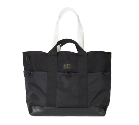 The MIS Multi Pocket Tote Bag - Black is made in the USA from Cordura nylon. It has two white shoulder straps, two black handles, two front zippered pockets, and a center rectangular MIS patch.