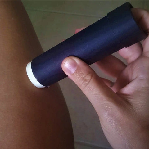 A hand applies the SOL TERRA SHOP Natural Lotion Bar 3-Pack to a bare thigh, showcasing the dark moisturizing bar against a softly blurred neutral background.