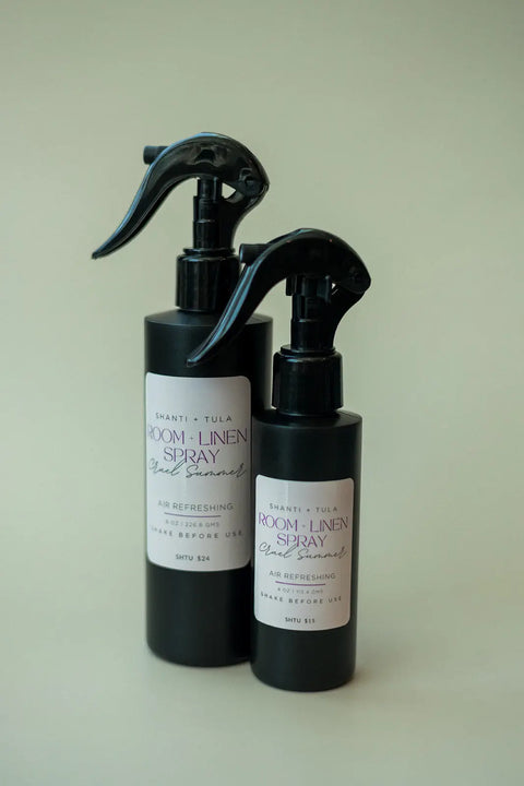 Two black bottles labeled “Shanti + Tula” stand side by side against a light background, featuring the Natural Room & Linen Spray – an odor neutralizer and air refresher, made in the USA by Shanti + Tula.