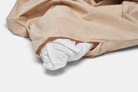 A close-up of the American Blossom Linens Natural Colored Cotton Duvet Cover Set in Foxfibre® coyote brown, partially open to show a white comforter inside with fabric corner ties against a plain white background.