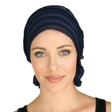 A woman with light skin and blue eyes wears the Chemo Beanies® Betty scarf in dark navy along with a black sleeveless top, looking directly at the camera against a plain white background.