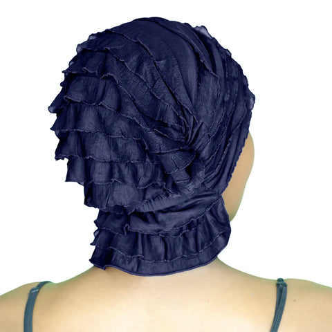 A person is seen from behind wearing the Chemo Beanies® Betty deep navy blue ruffled chemo beanie against a white background, with only their head, neck, and shoulders visible above a sleeveless top.