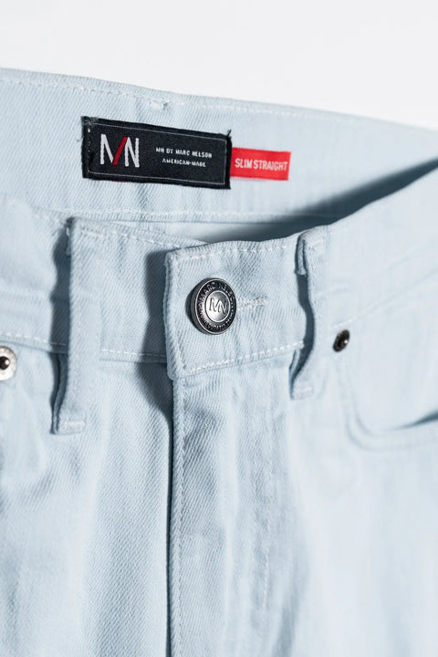 Close-up of The Nelson Ultra Light Wash Denim by Marc Nelson, showing the waistband, metal button, belt loops, black MN BY MARC NELSON label with red SLIM STRAIGHT tag. Classic 5-pocket style. Made in the USA.