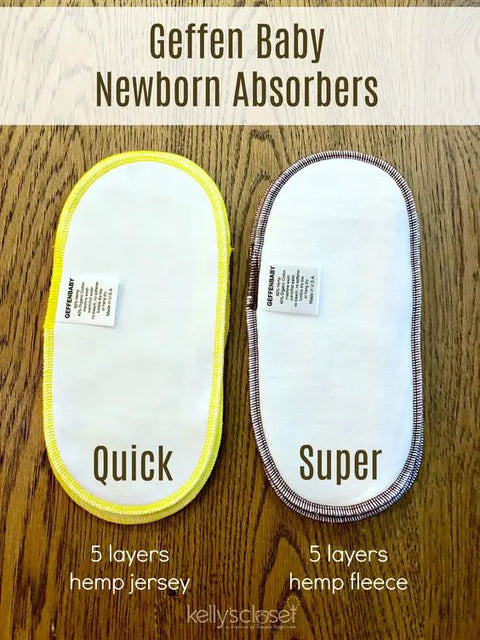 Two Geffenbaby Newborn Quick Absorbers Diaper Inserts rest on a wooden surface: the left, with yellow trim, is made of 5 layers of hemp jersey; the right, with brown trim, has 5 layers of hemp fleece. Both are reusable. Labels and tags are visible.