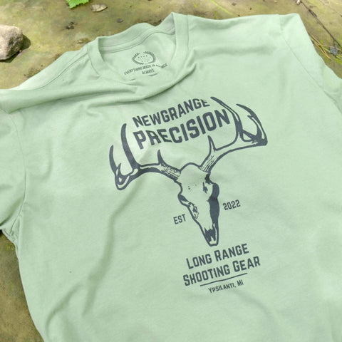 The Collab Tee: Newgrange Logo by American Lictor is a light green, soft ring-spun cotton shirt featuring a deer skull design and NEWGRANGE PRECISION, EST 2022, LONG RANGE SHOOTING GEAR, YPSILANTI, MI. See size guide for details.