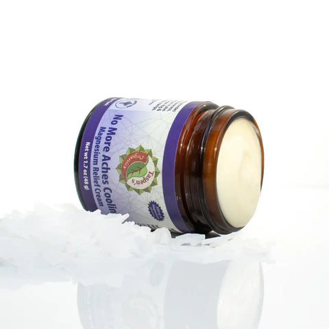 A Taspens Organics Magnesium No More Aches Cooling Relief Cream jar lies open on its side, showing the creamy inside. White flakes on the white surface highlight this muscle pain relief product.