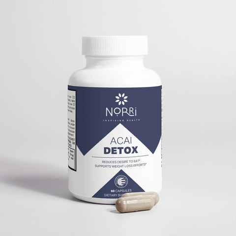 A bottle of Norri Nutrition Acai Detox, a supplement for appetite reduction and weight loss support, rests on a white surface with two beige capsules in front, its label emphasizing its benefits against a plain background.